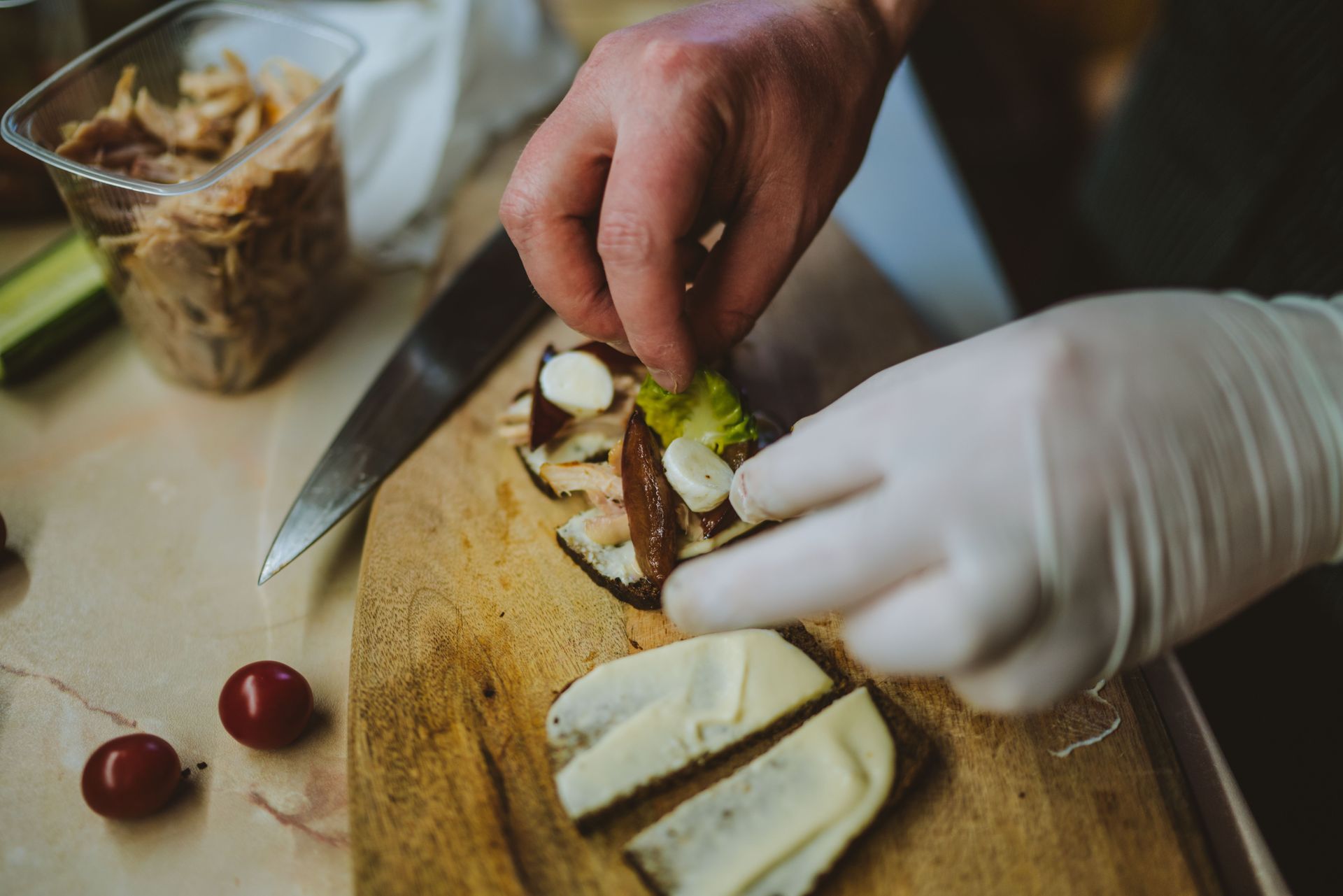 A chef arranges gourmet ingredients on bread slices, showcasing culinary precision.